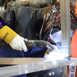  student leaning over aluminum bar with welding tools